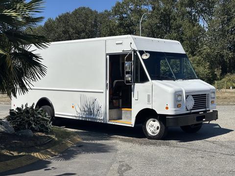 A white 2011 Ford E-450 delivery truck with an open side door and a front grill featuring a circular panel