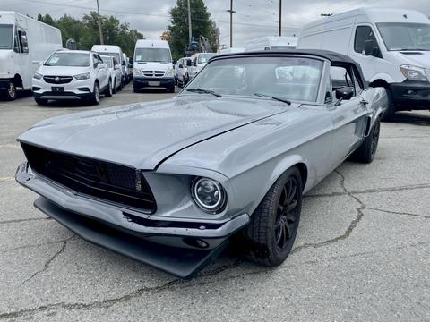 A 1968 Ford Mustang two-door convertible in gray with a black interior and sporty black wheels is prominently displayed