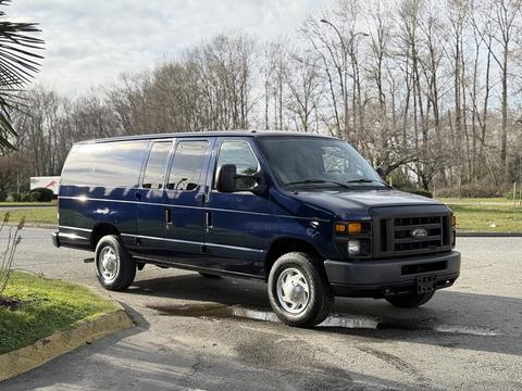 A blue 2011 Ford Econoline van parked at an angle with sliding side doors and a tall roof design