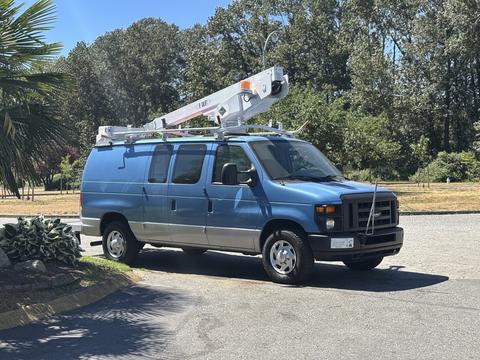 A blue 2008 Ford E-350 van with a utility ladder rack on top parked on a driveway