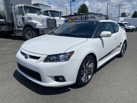 A white 2013 Scion TC with a sleek design and sporty features, showcasing alloy wheels and distinctive side decals