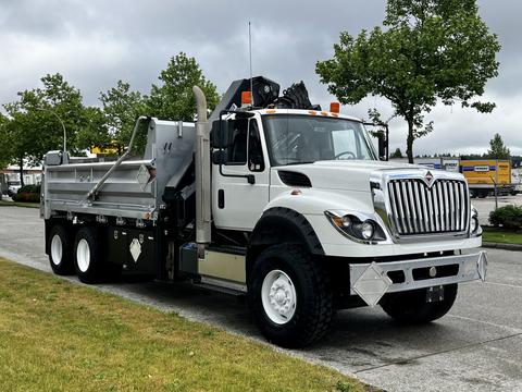 A 2017 International WorkStar 7600 truck with a silver and black body features a dump bed and large tires positioned for utility and off-road capability