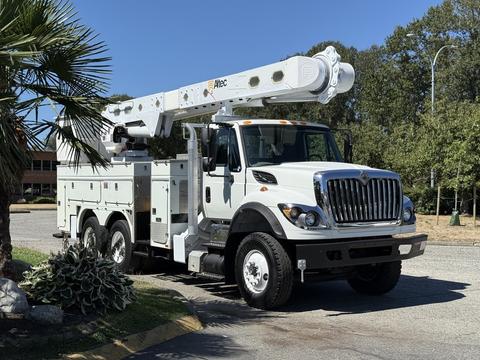 A 2013 International 7400 equipped with an aerial lift system featuring an extended boom and storage compartments on the side of the vehicle