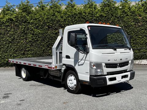 A 2013 Mitsubishi Fuso FE160 flatbed truck with a gray and white exterior and orange clearance lights on the roof