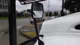 A 2010 International 4300 truck with a clear side mirror reflecting the surroundings and a rain-soaked surface on the hood