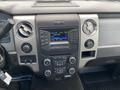 Dashboard of a 2013 Ford F-150 featuring radio display climate controls and various buttons and knobs