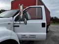 A 2008 Ford F-750 truck with a white cab and a red cargo trailer displaying weight specifications on the door