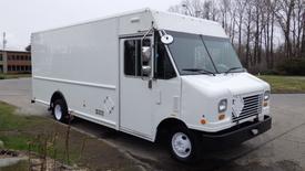 A white 2012 Ford Econoline delivery truck with a boxy shape and large front windows parked at an angle