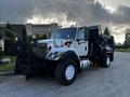 A 2011 International 7300 truck with a black dump bed and a snow plow attachment positioned at the front