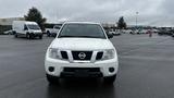 A white 2016 Nissan Frontier parked with a prominent front view showcasing its grille headlights and emblem