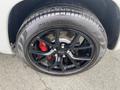 A close-up view of a black alloy wheel and tire from a 2018 Jeep Grand Cherokee showing red brake calipers and tire tread details