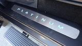 A close-up of the illuminated "PLATINUM" door sill plate of a 2017 Ford F-350 SD showcasing a sleek metallic finish