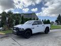 A white 2021 RAM 1500 pickup truck with black wheels and a bold grille parked outdoors