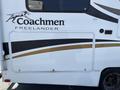 A 2012 Ford Econoline RV with a white exterior featuring black and gold accents and the "Coachmen Freelander" logo on the side