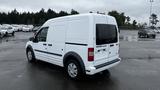 A white 2012 Ford Transit van parked with sliding side doors and a rear view showing large windows and a simple design