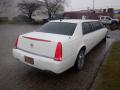 A white 2008 Cadillac Limousine with tinted windows and chrome wheels parked on a wet surface