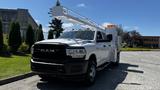 A white 2019 RAM 3500 with an elevated work platform attached to the bed showcasing its heavy-duty design and large front grille