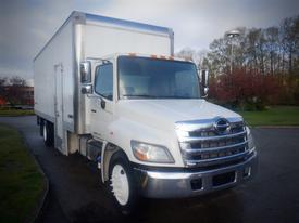 A 2013 Hino 308 box truck with a white exterior and a silver front grille is parked on a driveway