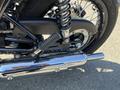 Close-up of a chrome exhaust on a 2019 Kawasaki W800 CAFÉ motorcycle showcasing the suspension and part of the rear wheel