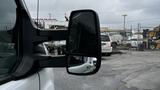 A side view mirror of a 2017 Ford Transit reflecting another vehicle in the distance