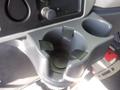 A close-up of a gray cup holder with three plastic inserts designed to hold cups securely inside a vehicle's interior console