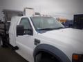 A white 2008 Ford F-550 with an extended cab and pickup bed featuring a flatbed attachment and multiple orange indicator lights on the roof