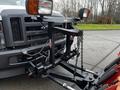 A 2009 Ford F-550 with a snow plow attachment mounted to the front featuring lights and a chain system.