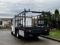 A 2005 Freightliner M2 106 truck with an open flatbed, metal framework for mounting equipment, and a utility box on the side