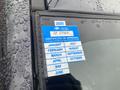 A blue 2024 certificate of approval sticker attached to the windshield of a 2014 Subaru Impreza with raindrops visible on the glass