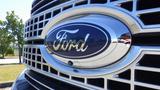 Close-up of a Ford emblem on the grille of a 2017 Ford F-350 SD with a shiny chrome finish and a blue oval background