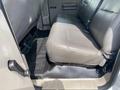 The interior of a 2010 Ford F-550 featuring a rear bench seat in gray leather with a rubber floor mat and seatbelt visible