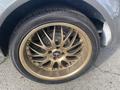 Close-up of a bronze alloy wheel on a 1966 Ford Mustang featuring a distinctive spoke design and the Mustang emblem in the center