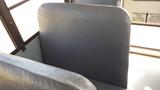 A gray bus seat from a 2014 International 3000 with a textured surface and backing visible in the foreground