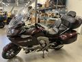 A maroon 2013 BMW K1600GTL motorcycle with a sleek design featuring a large windshield and a comfortable dual seat with backrests