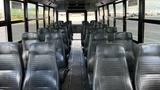 Interior view of a 2014 Freightliner Thomas Diesel bus featuring rows of black vinyl seats arranged along the aisle