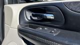 Close-up of the interior door panel of a 2016 Dodge Grand Caravan featuring a chrome door handle and window controls