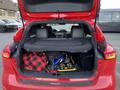 A red 2018 Ford Focus with the trunk open showing a blanket and tools inside