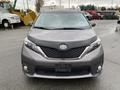 A 2013 Toyota Sienna in a gray color with a prominent front grille and sleek headlight design is positioned front facing