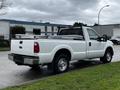 A white 2011 Ford F-250 SD pickup truck with a metal bed cover and a toolbox in the truck bed