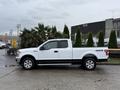 A white 2018 Ford F-150 truck parked with a crew cab and aftermarket wheels showcasing the 4x4 emblem on the side