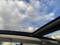 A 2015 Fiat 500L with a sunroof showing clouds in the sky above