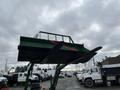 A 2003 John Deere 790 tractor with a large bucket attachment raised overhead