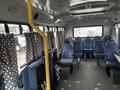 Interior view of a 2012 Chevrolet Express bus featuring blue fabric seats and decorative curtain panels along the windows