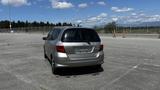 A silver 2006 Honda Fit parked with its rear facing the viewer