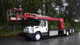 A 2010 International 4300 truck equipped with a red hydraulic lift system extended above the cab