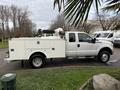 A white 2013 Ford F-350 SD truck with a utility body designed for work, featuring storage compartments and equipment mounted in the bed