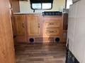 Interior view of a 2012 Ford Econoline showing wooden cabinetry with drawers and a countertop alongside a portable stovetop