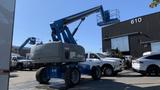 A 2008 Genie S-65 Boom Lift with a gray body and blue arm extended upwards ready for use