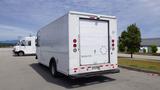 A white 2011 Ford Econoline cargo van with a blank rear door and red taillights parked in a lot