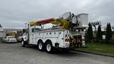 A 2006 International 7500 bucket truck with a yellow and red articulated arm attached to a white body with storage compartments